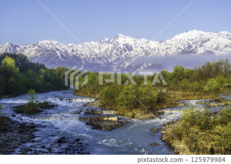 Fresh greenery and snow-capped Northern Alps seen from Matsukawa Bridge in Hakuba Village Fresh greenery and snow-capped Northern Alps seen from Matsukawa Bridge in Hakuba Village 125979984