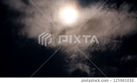 Full moon and starry night sky shining through the clouds 125981038