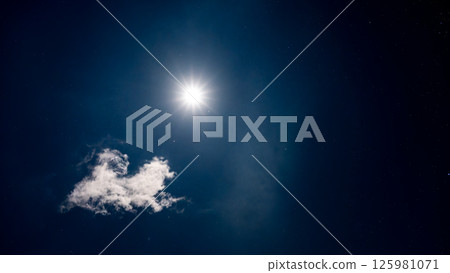 Full moon and starry night sky shining through the clouds 125981071