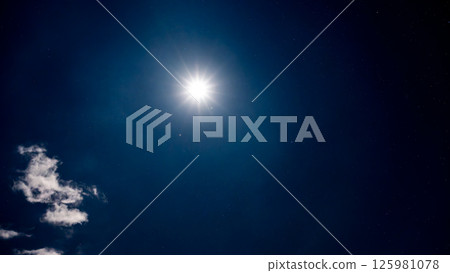 Full moon and starry night sky shining through the clouds 125981078