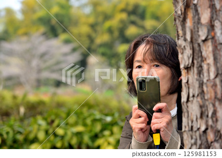 Woman taking a photo with a mobile phone camera Woman taking a photo with a mobile phone camera 125981153