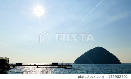 A scene of the setting sun casting a silver band over the sea surface between the pier at Asamushi Sea Fishing Park and Yunoshima Island, Aomori City, Aomori Prefecture 125982501