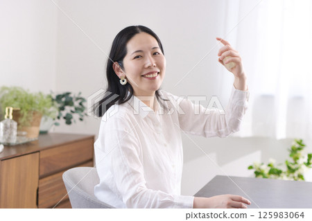 A smiling middle-aged woman spraying moisturizing spray on her face A smiling middle-aged woman spraying moisturizing spray on her face 125983064
