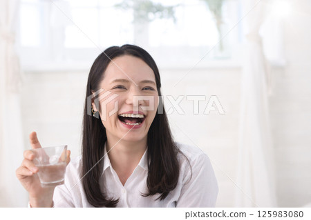 Middle woman drinking water in the living room 125983080