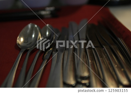 Spoons knives cloth rustic flatware set consisting of a spoon, fork, and knife arranged on a grey cloth napkin, evoking vintage charm and functionality. 125983155