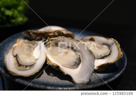 Fresh oysters on ice served with lemon wedges and rosemary, perfect for gourmet seafood lovers Fresh oysters on ice served with lemon wedges and rosemary, perfect for gourmet seafood lovers 125983189