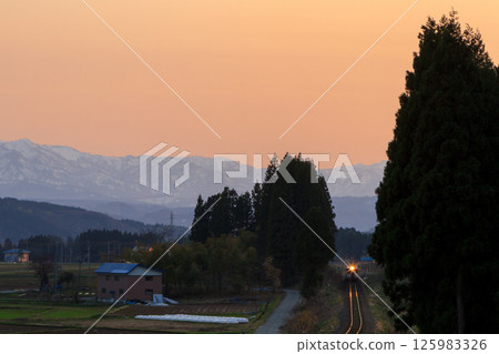 The Rikuu East Line plods along with its headlights shining in the silence of dusk. 125983326