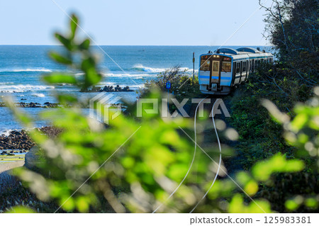 A Hachinohe Line diesel train speeds along the coast of Shukudo with the Pacific Ocean in the background. A Hachinohe Line diesel train speeds along the coast of Shukudo with the Pacific Ocean in the background. 125983381
