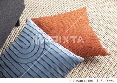 Stylish living room interior with orange, blue, red pillow on sofa, wooden coffee table and olive tree in a pot. 125983769