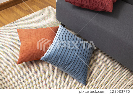 Stylish living room interior with orange, blue, red pillow on sofa, wooden coffee table and olive tree in a pot. 125983770