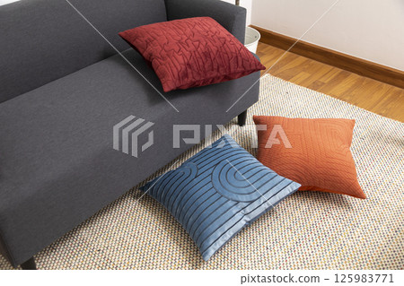 Stylish living room interior with orange, blue, red pillow on sofa, wooden coffee table and olive tree in a pot. Stylish living room interior with orange, blue, red pillow on sofa, wooden coffee table and olive tree in a pot. 125983771