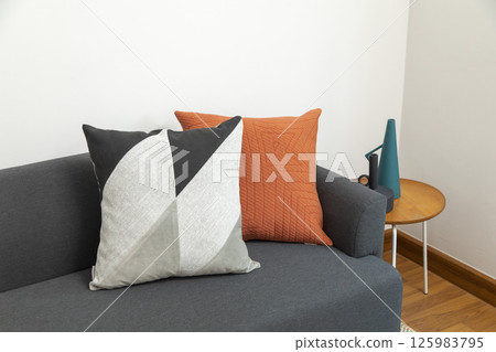 Stylish living room interior with orange, red blue, yellow pillow on sofa, wooden coffee table and olive tree in a pot. 125983795