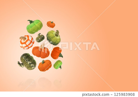 Flying knitted orange and green pumpkins orange background with a place for the text. Concept of autumn, Halloween, Thanksgiving. Diy Home Decor. Knitting toys and decorations for home 125983908