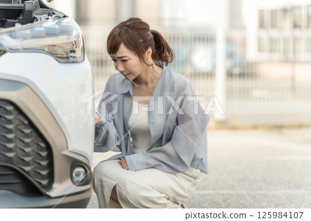Female driver crashing her car and looking at the bumper Female driver crashing her car and looking at the bumper 125984107