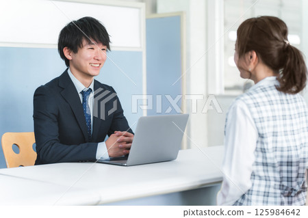 Young Asian businessman serving female customers at reception desk Young Asian businessman serving female customers at reception desk 125984642