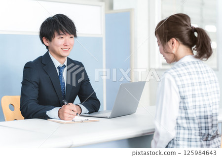 Young Asian businessman serving female customers at reception desk 125984643