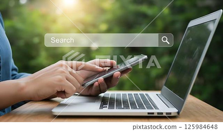 Woman using laptop and phone, online search 125984648