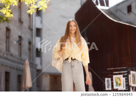 Young woman enjoying a sunny day while walking in urban art space with her casual outfit and smiling happily outdoors Young woman enjoying a sunny day while walking in urban art space with her casual outfit and smiling happily outdoors 125984945
