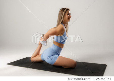 Woman practicing advanced yoga pose indoors during a fitness routine in a bright setting 125984965