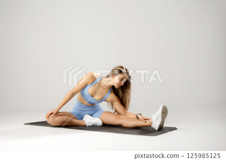Fitness enthusiast stretching on a yoga mat during a workout session in a bright studio environment Fitness enthusiast stretching on a yoga mat during a workout session in a bright studio environment 125985125