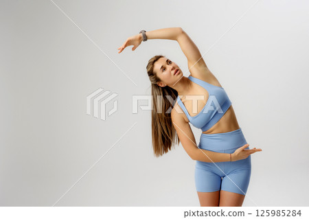 Fitness enthusiast stretches gracefully in a studio setting during a workout session focused on flexibility and wellness 125985284