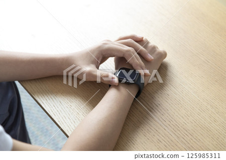 business, technology and people concept - close up of male hand wearing watch at wooden table business, technology and people concept - close up of male hand wearing watch at wooden table 125985311