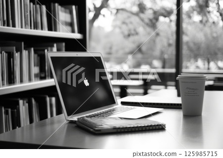 Working on a laptop in a quiet library with coffee and notebooks during a peaceful afternoon Working on a laptop in a quiet library with coffee and notebooks during a peaceful afternoon 125985715