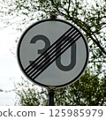 End of speed limit sign showing 30 kmh with trees in background 125985979
