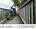 Electric bicycle towing small caravan crossing narrow bridge in countryside 125985980