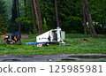 Camper enjoying camping with motorcycle and micro caravan in the woods 125985981