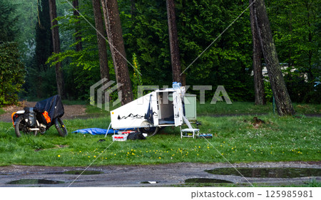Camper enjoying camping with motorcycle and micro caravan in the woods 125985981