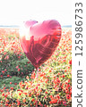Heart-shaped balloon floating above a vibrant field of red poppies, evoking love and joy on a sunny day 125986733