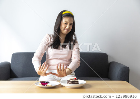 Woman on dieting for good health concept. Woman doing cross arms sign to refuse junk food or fast food Woman on dieting for good health concept. Woman doing cross arms sign to refuse junk food or fast food 125986916