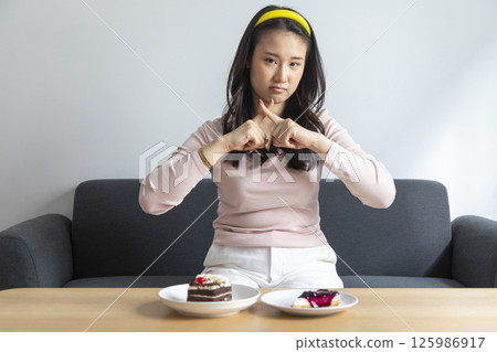 Woman on dieting for good health concept. Woman doing cross arms sign to refuse junk food or fast food Woman on dieting for good health concept. Woman doing cross arms sign to refuse junk food or fast food 125986917
