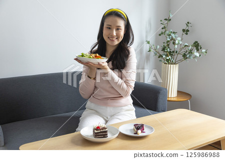 healthy eating, dieting and people concept - close up of young woman eating vegetable salad at home 125986988