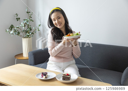 healthy eating, dieting and people concept - close up of young woman eating vegetable salad at home 125986989