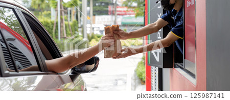 Hand Man in car receiving coffee in drive thru fast food restaurant. 125987141