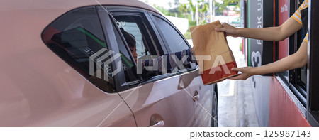 Hand Man in car receiving coffee in drive thru fast food restaurant. 125987143