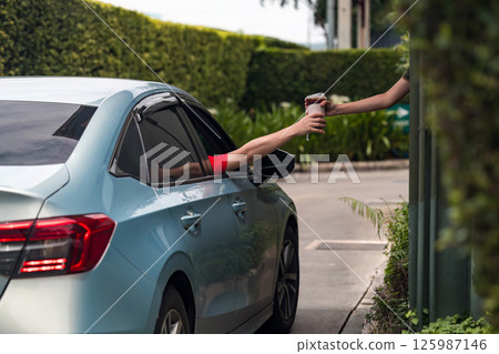 Hand Man in car receiving coffee in drive thru fast food restaurant. 125987146