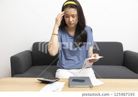beautiful sad woman at home living room couch calculating monthly expenses worried in stress with bank papers and documents in paying taxes mortgage debt and cost of living concept beautiful sad woman at home living room couch calculating monthly expenses worried in stress with bank papers and documents in paying taxes mortgage debt and cost of living concept 125987193