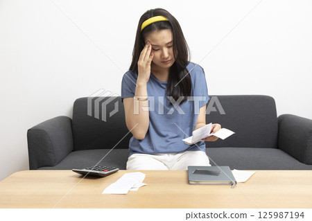 beautiful sad woman at home living room couch calculating monthly expenses worried in stress with bank papers and documents in paying taxes mortgage debt and cost of living concept beautiful sad woman at home living room couch calculating monthly expenses worried in stress with bank papers and documents in paying taxes mortgage debt and cost of living concept 125987194