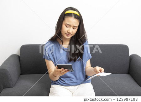 beautiful sad woman at home living room couch calculating monthly expenses worried in stress with bank papers and documents in paying taxes mortgage debt and cost of living concept beautiful sad woman at home living room couch calculating monthly expenses worried in stress with bank papers and documents in paying taxes mortgage debt and cost of living concept 125987198