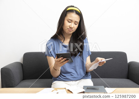beautiful sad woman at home living room couch calculating monthly expenses worried in stress with bank papers and documents in paying taxes mortgage debt and cost of living concept beautiful sad woman at home living room couch calculating monthly expenses worried in stress with bank papers and documents in paying taxes mortgage debt and cost of living concept 125987200