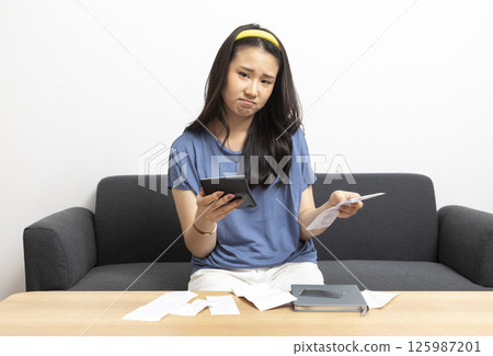beautiful sad woman at home living room couch calculating monthly expenses worried in stress with bank papers and documents in paying taxes mortgage debt and cost of living concept beautiful sad woman at home living room couch calculating monthly expenses worried in stress with bank papers and documents in paying taxes mortgage debt and cost of living concept 125987201