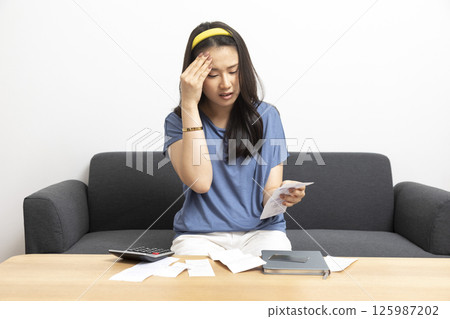 beautiful sad woman at home living room couch calculating monthly expenses worried in stress with bank papers and documents in paying taxes mortgage debt and cost of living concept 125987202