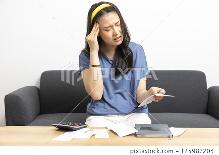 beautiful sad woman at home living room couch calculating monthly expenses worried in stress with bank papers and documents in paying taxes mortgage debt and cost of living concept 125987203