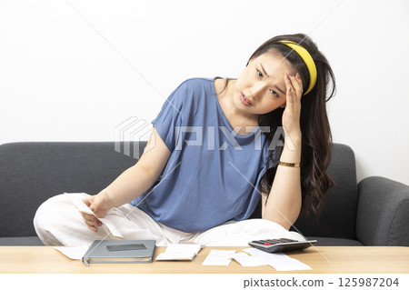 beautiful sad woman at home living room couch calculating monthly expenses worried in stress with bank papers and documents in paying taxes mortgage debt and cost of living concept 125987204