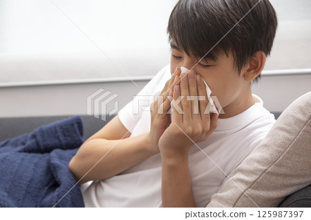 boy blow his nose. Sick child with napkin in bed. Allergic kid, flu season. Kid with cold rhinitis, get cold snot nose 125987397