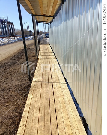 Construction walkway along a metal structure at a development site during early spring 125987436