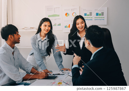 Team of financial advisory services. Asian advisor showing plan of investment to clients in the consultancy office. 125987867